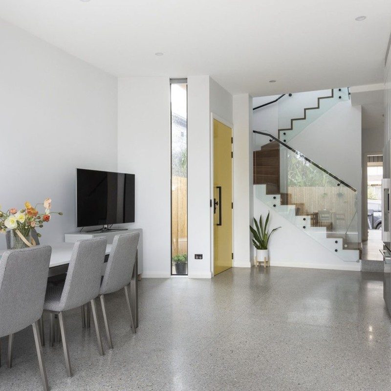 Open-plan dining and living on polished concrete, looking through to the stairwell of a first-floor addition, Lewisham